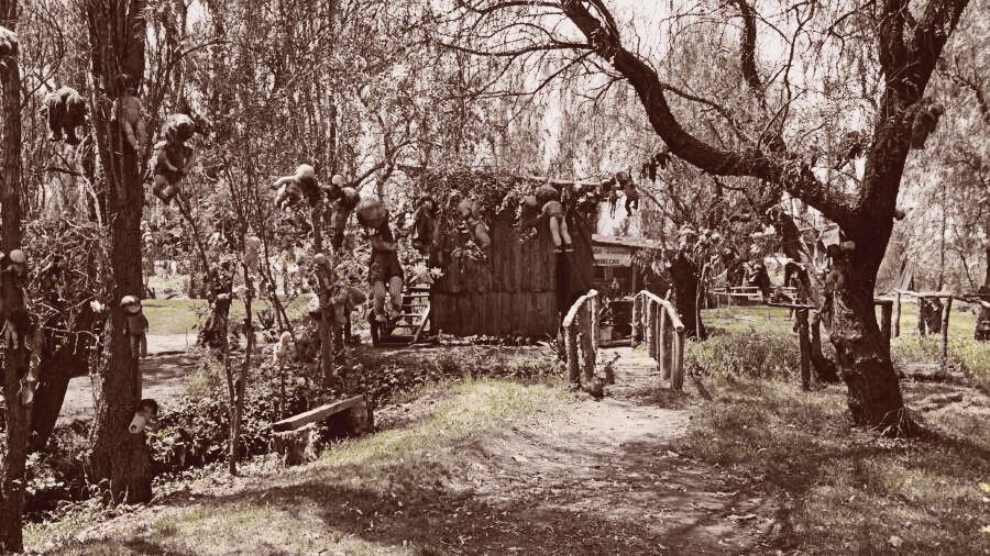 A simple wood house with dolls hung on it.